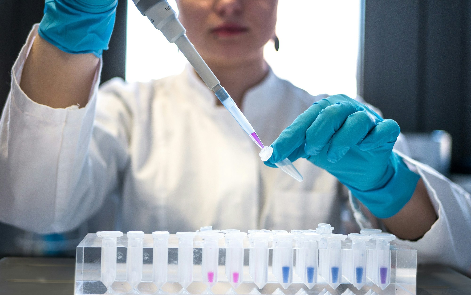 Scientist pipetting into a row of laboratory sample tubes